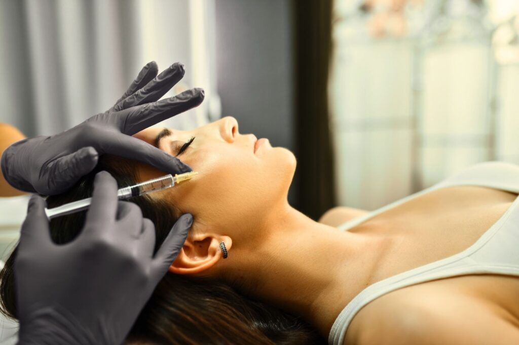 Aesthetic practitioner administering a facial injectable treatment in a clinical setting following UK safety standards